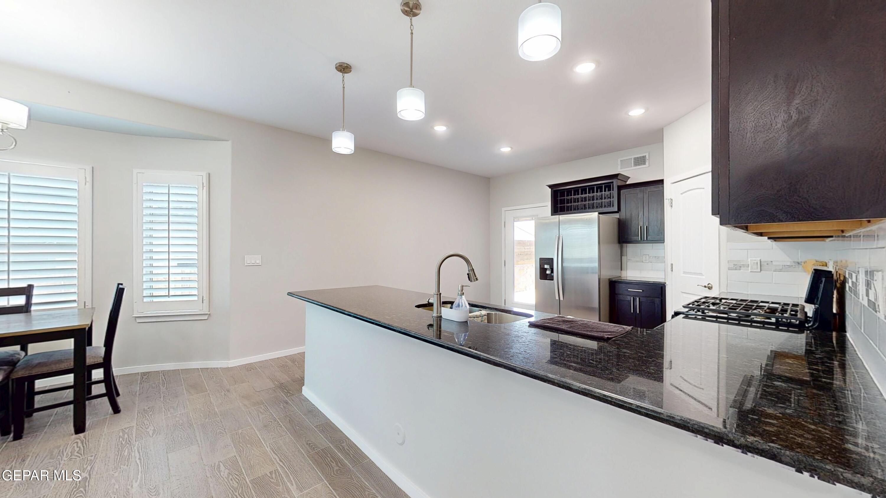 219 Notts Way El Paso, TX 79928 - Photo 7 of 35 a kitchen with granite countertop a stove a sink a dining table and chairs with wooden floor