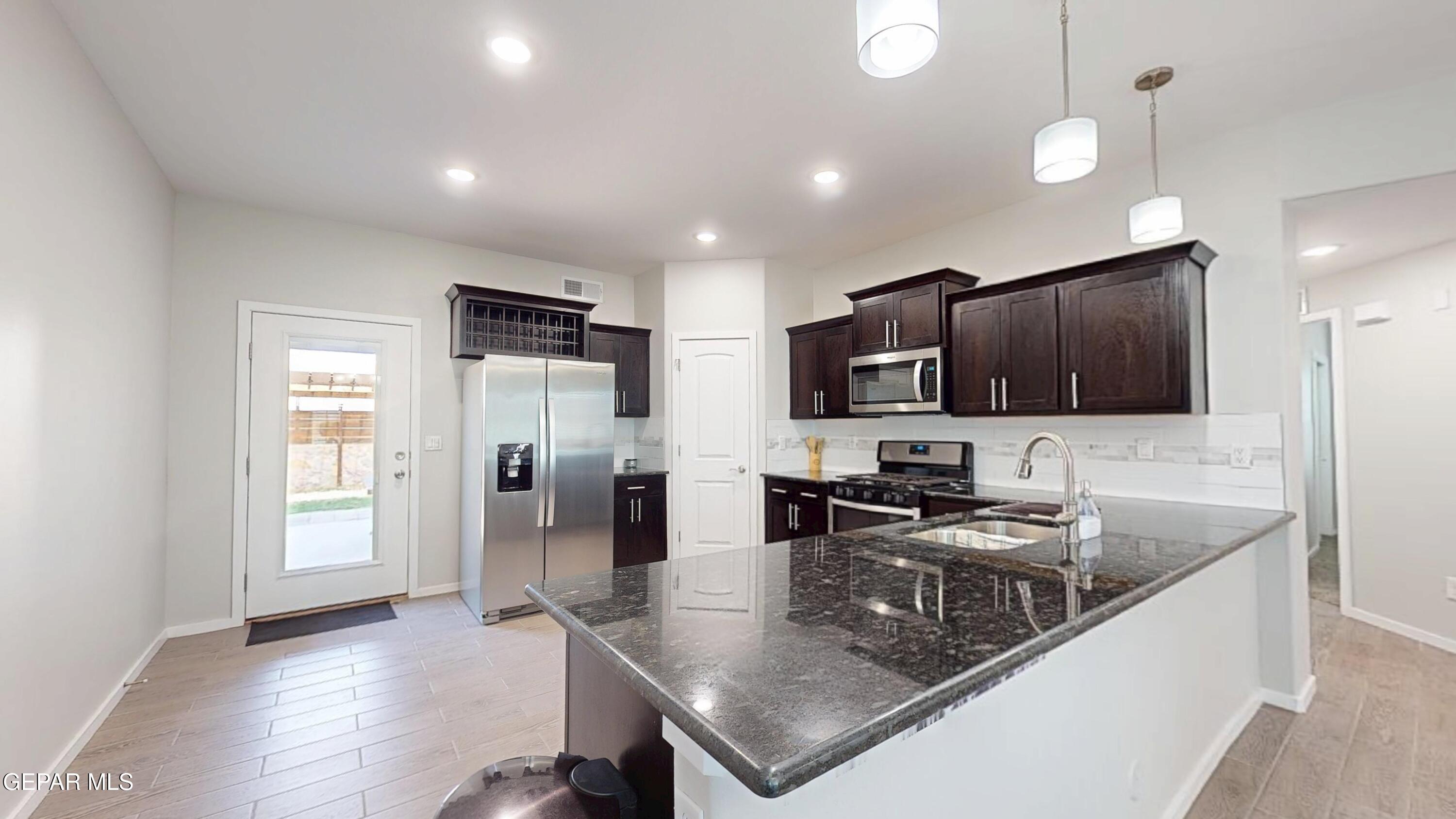 219 Notts Way El Paso, TX 79928 - Photo 9 of 35 a kitchen with stainless steel appliances granite countertop a sink refrigerator and cabinets