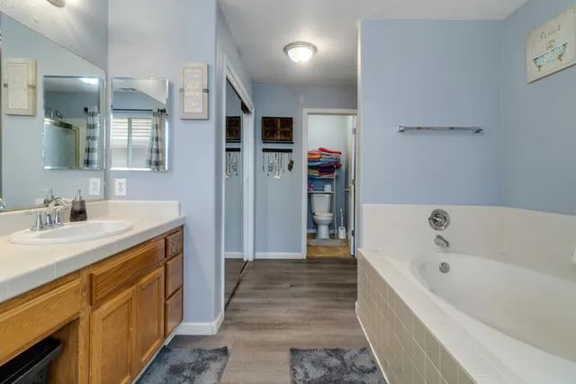 a spacious bathroom with a tub sink and mirror