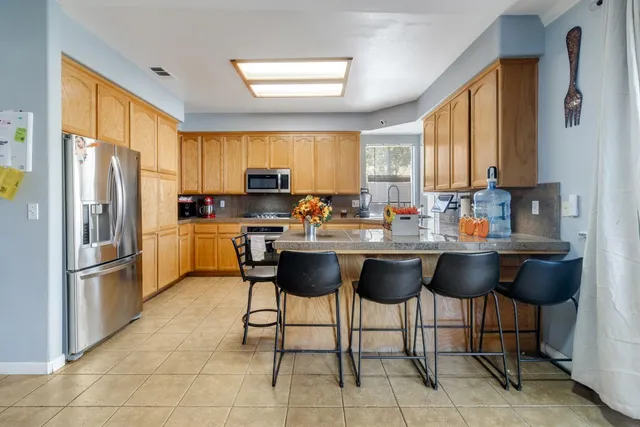 a kitchen with stainless steel appliances granite countertop a refrigerator table and chairs