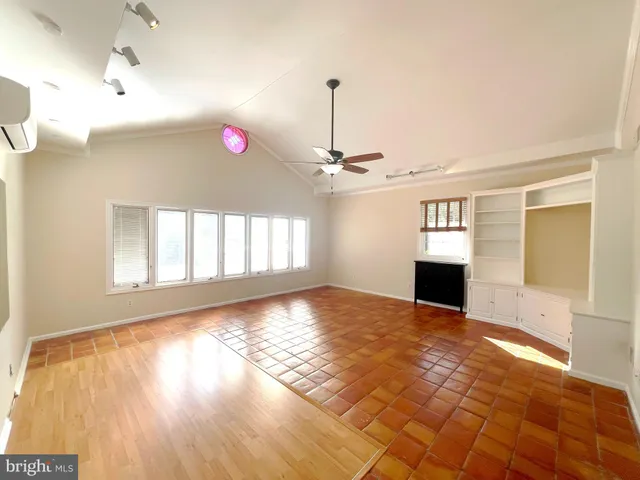 a view of empty room with wooden floor and fan