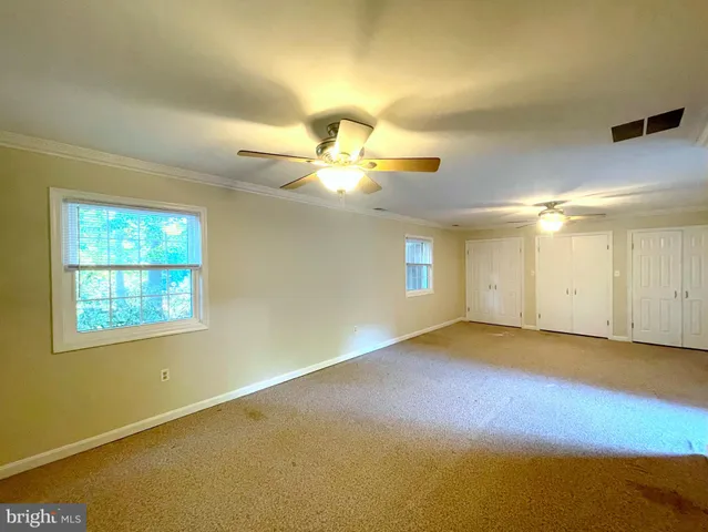 an empty room with a bathroom and a chandelier fan