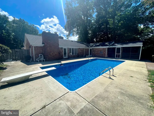 a view of a swimming pool with lounge chair and trees
