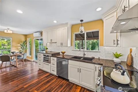 a kitchen with stainless steel appliances a stove a sink dishwasher a microwave oven with cabinets and wooden floor