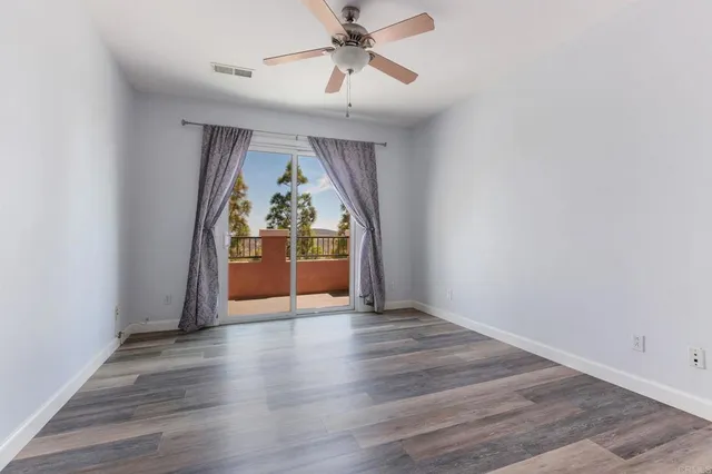 a view of a room with wooden floor and ceiling fan