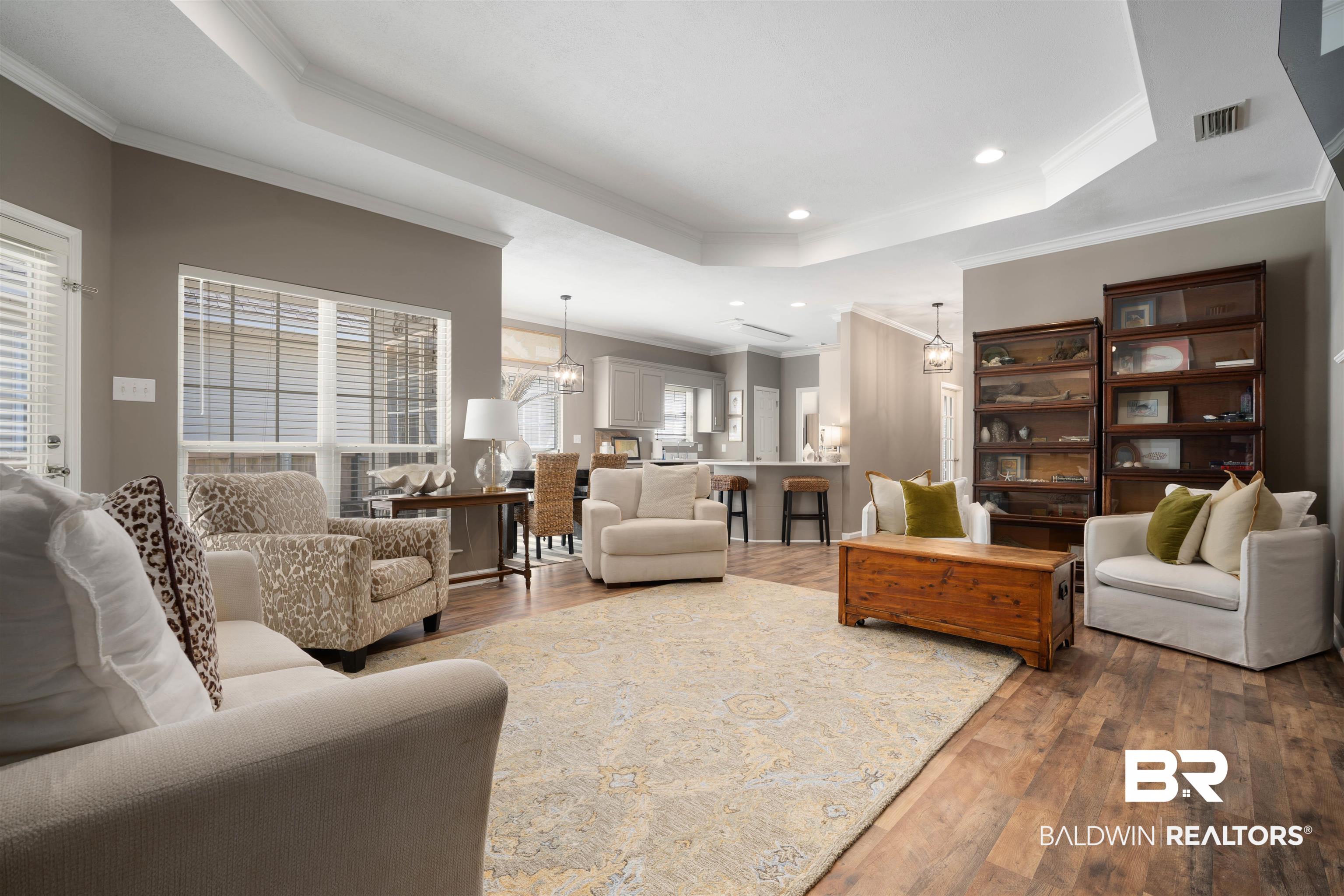 27288 Parker Lane Daphne, AL 36526 - Photo 3 of 29 Living room with a chandelier, a raised ceiling, hardwood / wood-style flooring, ornamental molding, and recessed lighting