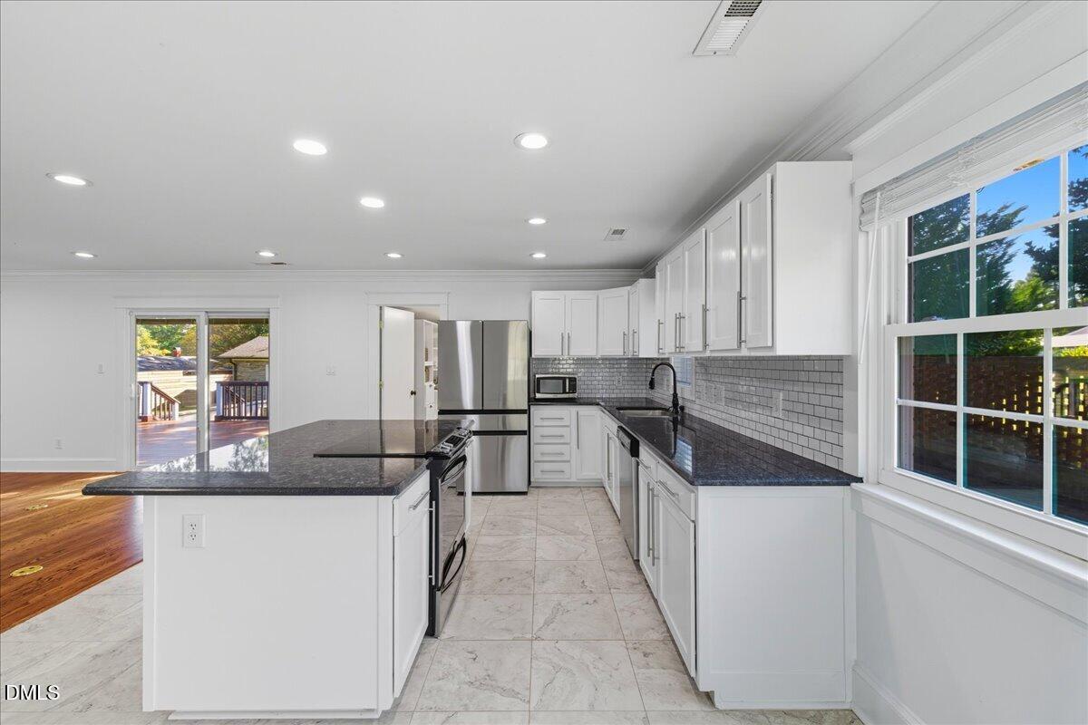 709 Winterlochen Road Raleigh, NC 27603 - Photo 13 of 52 a kitchen with stainless steel appliances kitchen island granite countertop a sink and cabinets