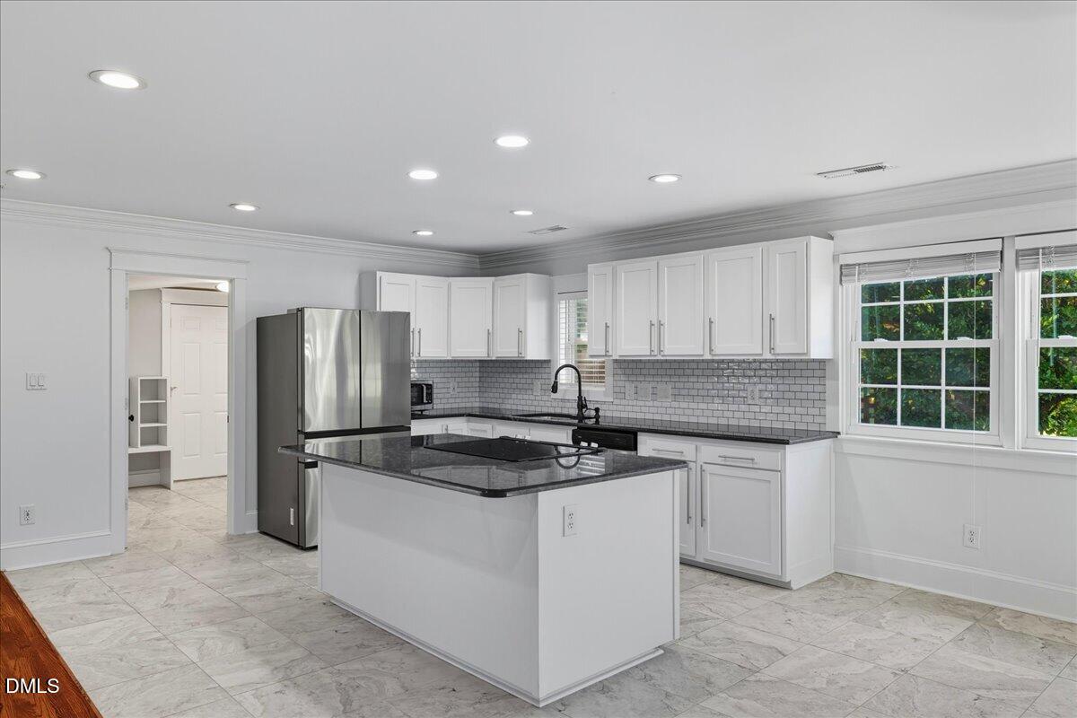 709 Winterlochen Road Raleigh, NC 27603 - Photo 14 of 52 a kitchen with stainless steel appliances granite countertop a stove a refrigerator a sink and white cabinets with wooden floor