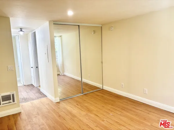 a view of a hallway with wooden floor and a bathroom