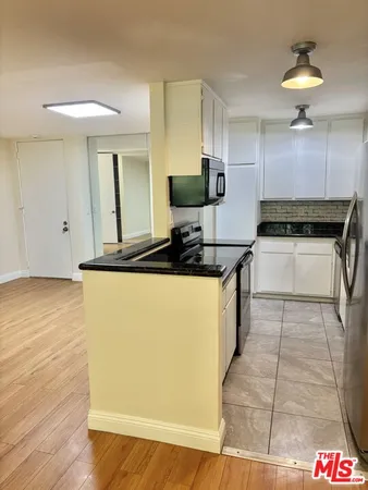 a kitchen with kitchen island granite countertop a stove and a refrigerator