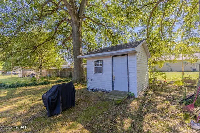 a view of a backyard with plants and large tree