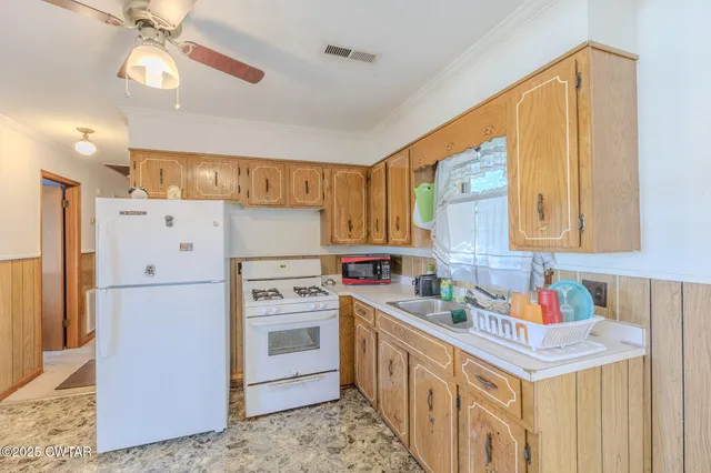 a kitchen with stainless steel appliances granite countertop a refrigerator a stove a sink dishwasher and white cabinets with wooden floor