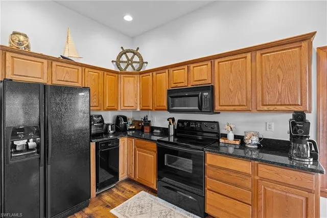 a kitchen with stainless steel appliances granite countertop a stove top oven a sink dishwasher a dining table and chairs with wooden floor