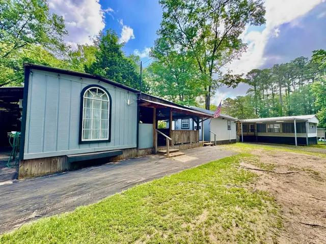 a view of a house with a yard plants and large tree