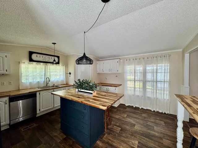 a kitchen with stainless steel appliances a refrigerator a sink dishwasher a stove and white countertops with wooden floor