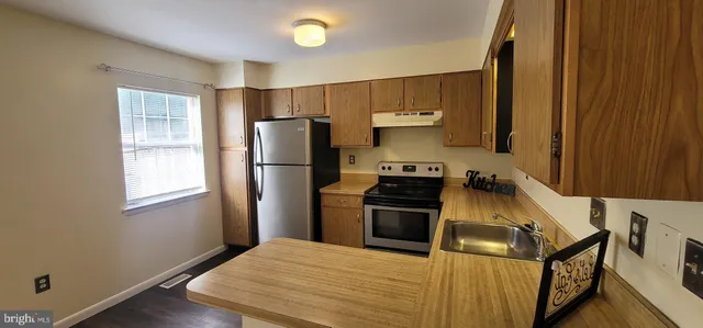 a kitchen with granite countertop a refrigerator stove and sink