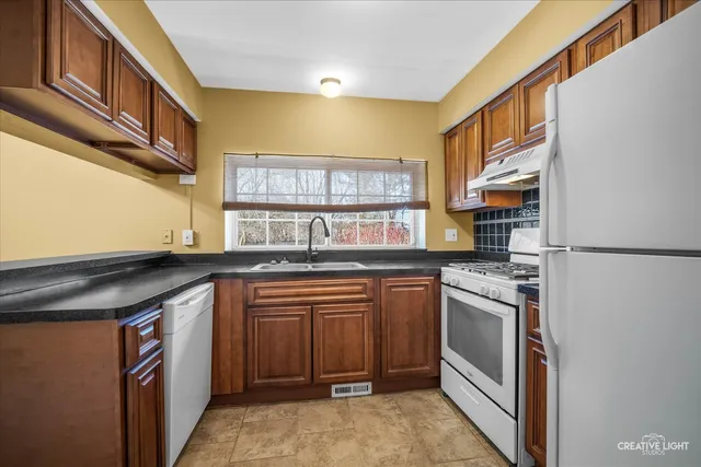 a kitchen with stainless steel appliances granite countertop a stove a sink and a refrigerator
