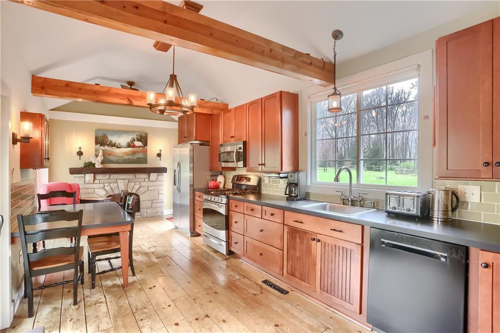 316 Denny Road Valencia, PA 16059 - Photo 6 of 49 Gorgeously updated eat in kitchen features exposed beams, hardwood floors, abundant custom cabinetry, endless counters and a glass backsplash.