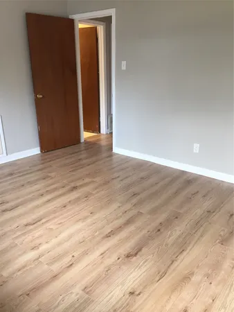 a view of an empty room with wooden floor and closet