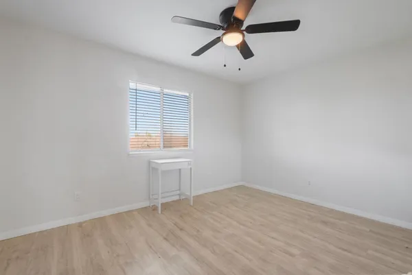 an empty room with a window and a fan