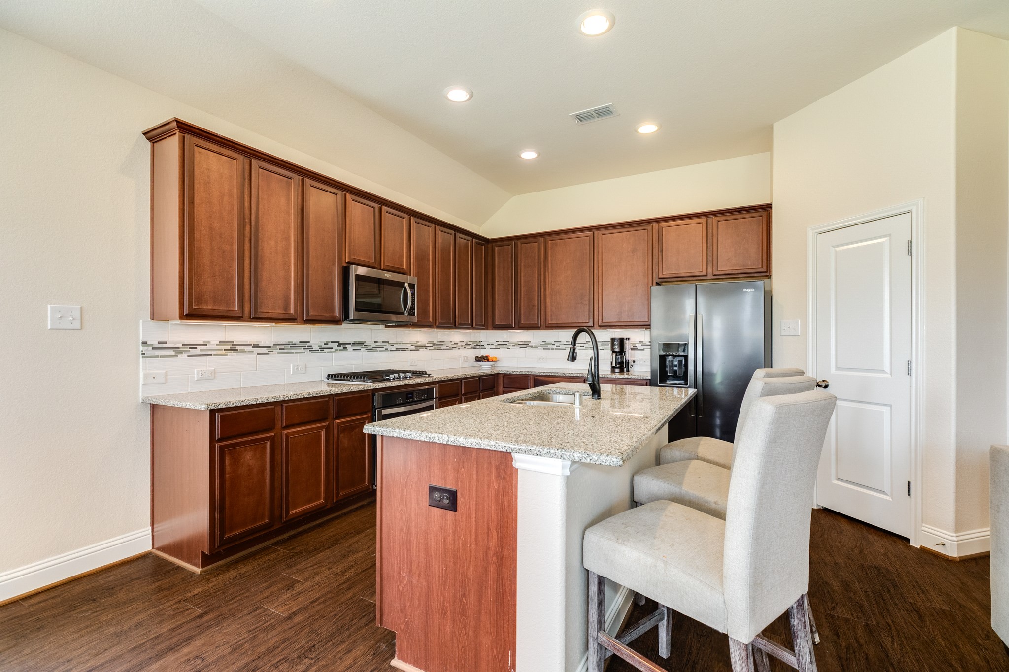 3519 Bay Drive Rosharon, TX 77583 - Photo 16 of 49 Modern kitchen featuring spacious granite countertops that serve as an ideal breakfast bar. To the right, a dedicated pantry door provides convenient access for storage. The space is further enhanced by elegant recessed lighting, creating a bright and inviting atmosphere.