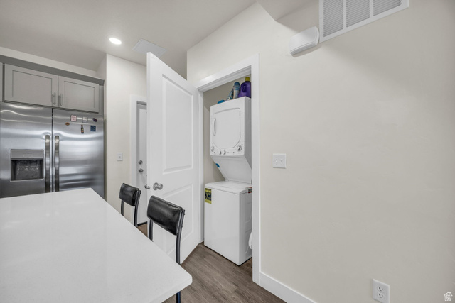 2101 North Main Street, Unit 409 Sunset, UT 84015 - Photo 3 of 18 Kitchen featuring stainless steel refrigerator with ice dispenser, stacked washer and dryer, a kitchen bar, dark wood-type flooring, and gray cabinetry