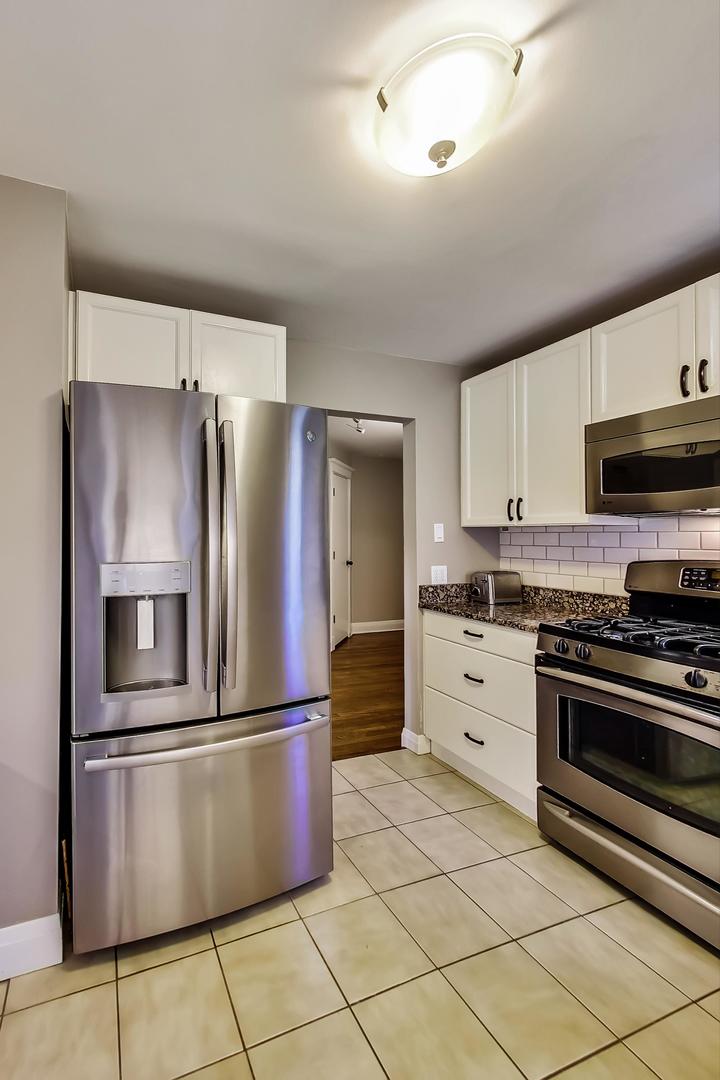 4214 North Kenmore Avenue, Unit 2F Chicago, IL 60613 - Photo 11 of 23 a kitchen with stainless steel appliances granite countertop a refrigerator a stove a sink and a microwave