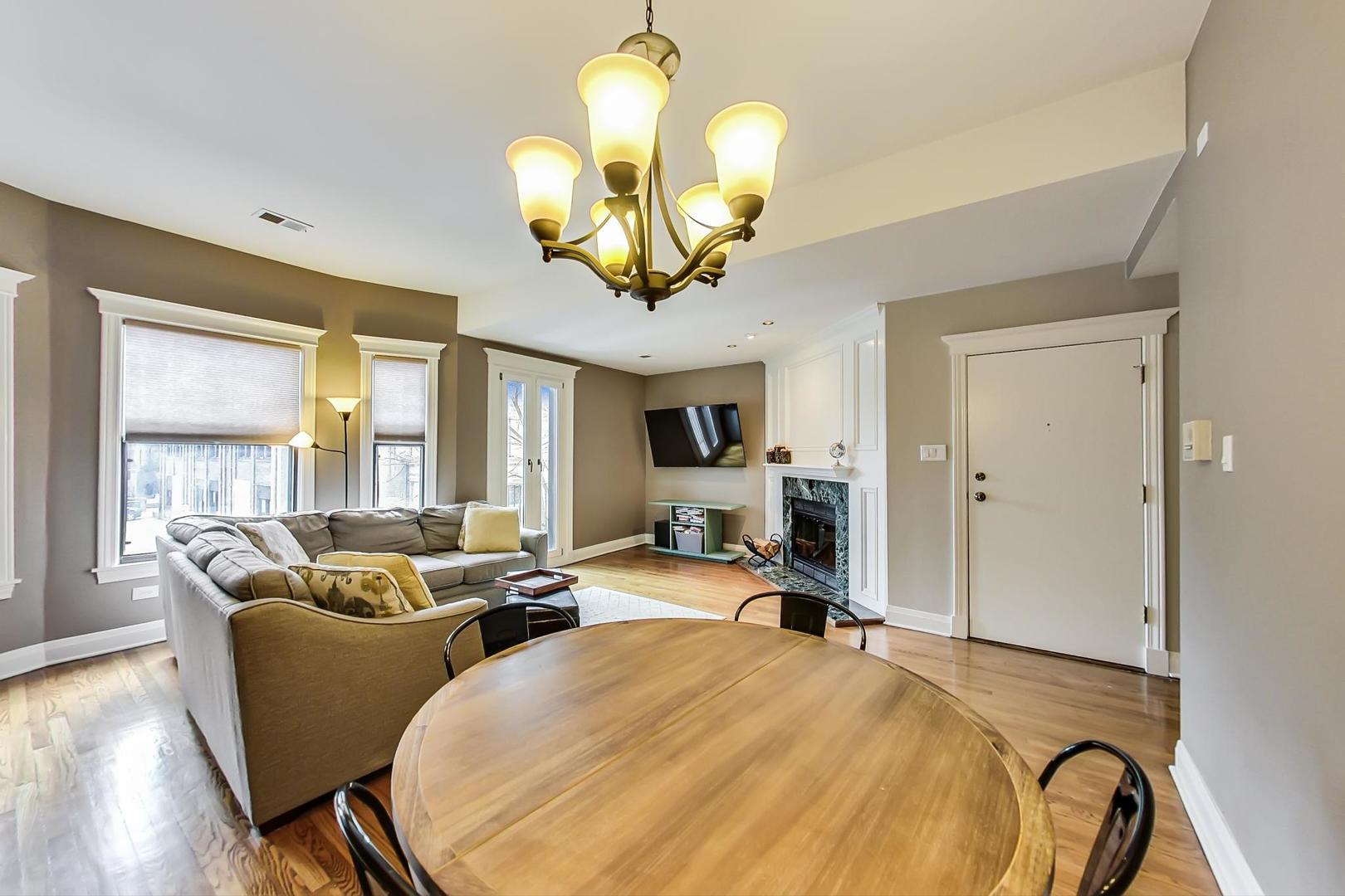 4214 North Kenmore Avenue, Unit 2F Chicago, IL 60613 - Photo 8 of 23 a living room with furniture a chandelier and a large window