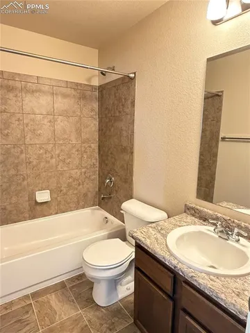 a bathroom with a granite countertop sink toilet mirror and bathtub
