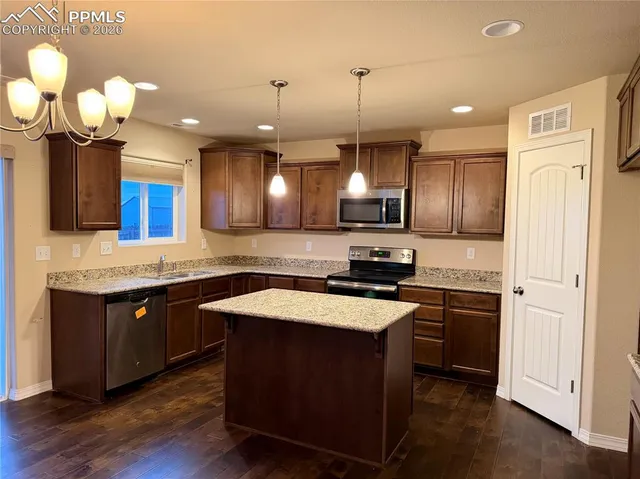 a kitchen with a sink stainless steel appliances and wooden floor