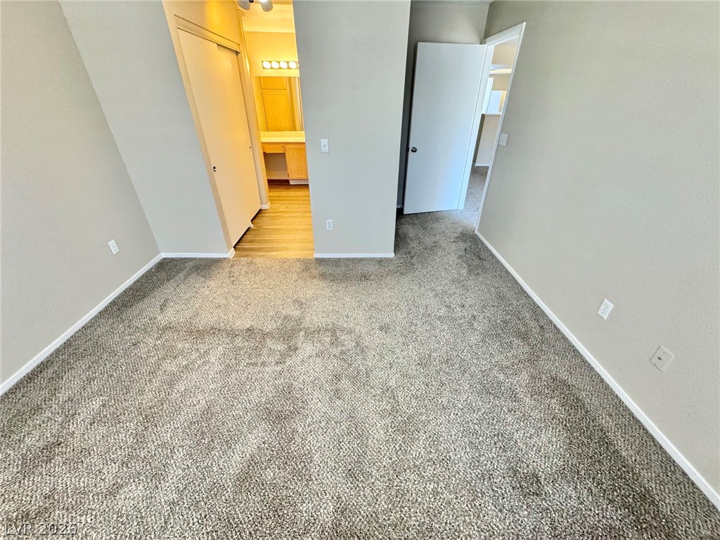 8070 West Russell Road, Unit 2121 Las Vegas, NV 89113 - Photo 14 of 22 Plush carpeting creates a cozy retreat, leading to a vanity area with wood-look flooring.