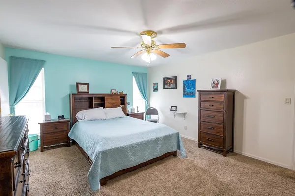 a bedroom with a bed a dresser and a chandelier