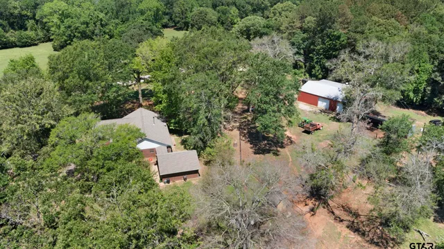 an aerial view of a house with a yard and trees all around