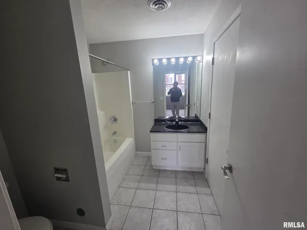 a bathroom with a granite countertop sink a mirror and a bathtub