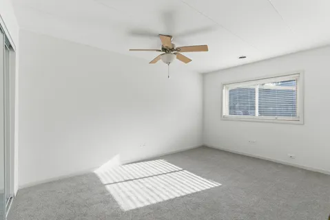 an empty room with a window and a ceiling fan