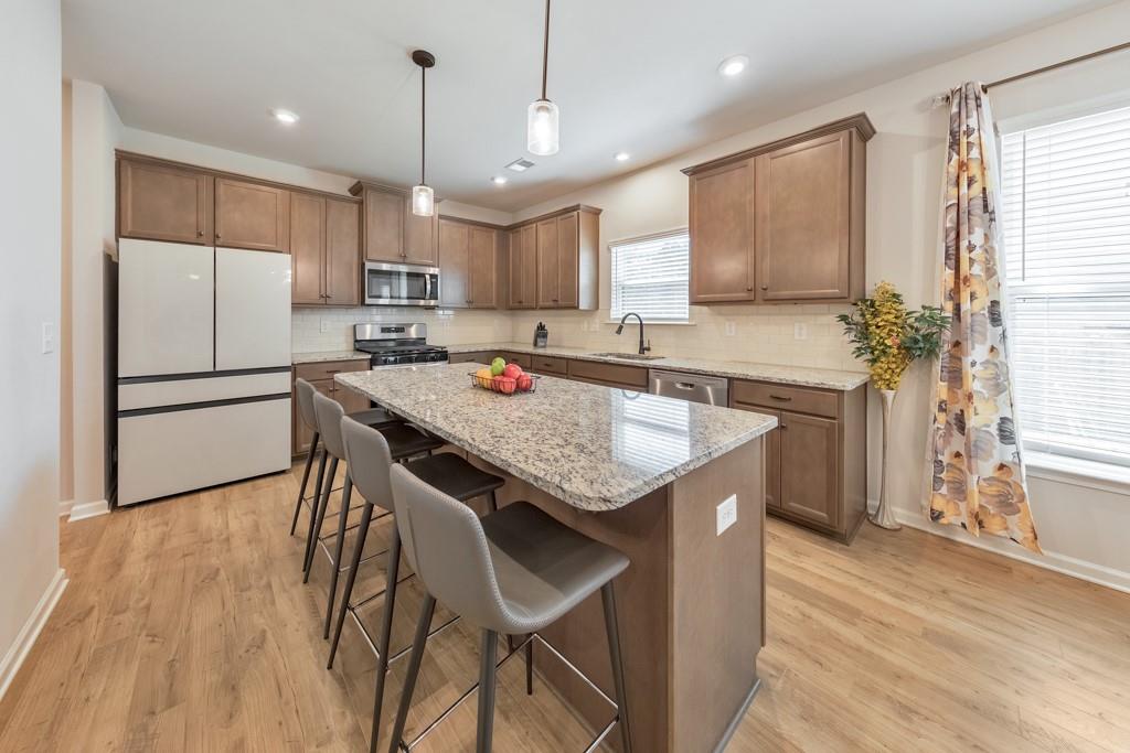 3146 Dowsing Lane Powder Springs, GA 30127 - Photo 7 of 42 a kitchen with stainless steel appliances granite countertop a kitchen island a stove a refrigerator a sink a dining table and chairs with wooden floor