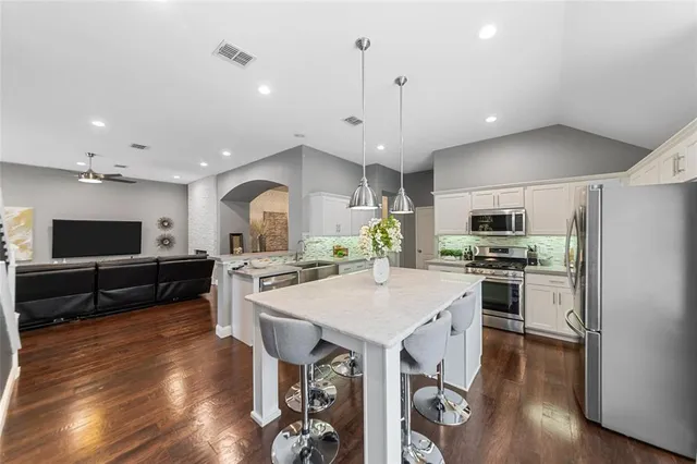 a large kitchen with a table chairs stainless steel appliances and wooden floor