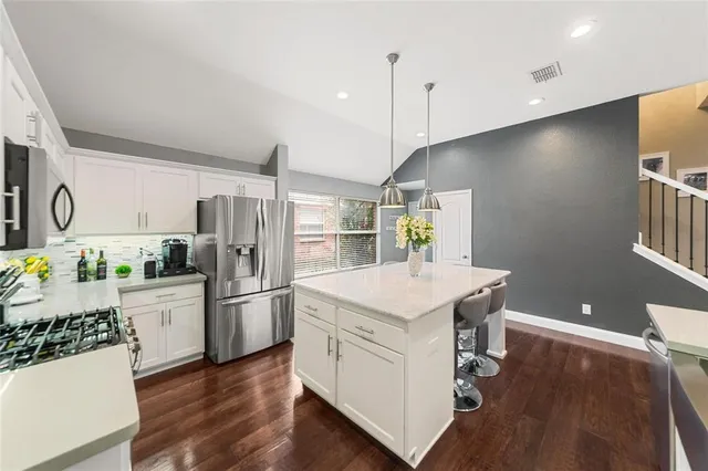 a kitchen with a refrigerator a sink dishwasher and a stove with wooden floor