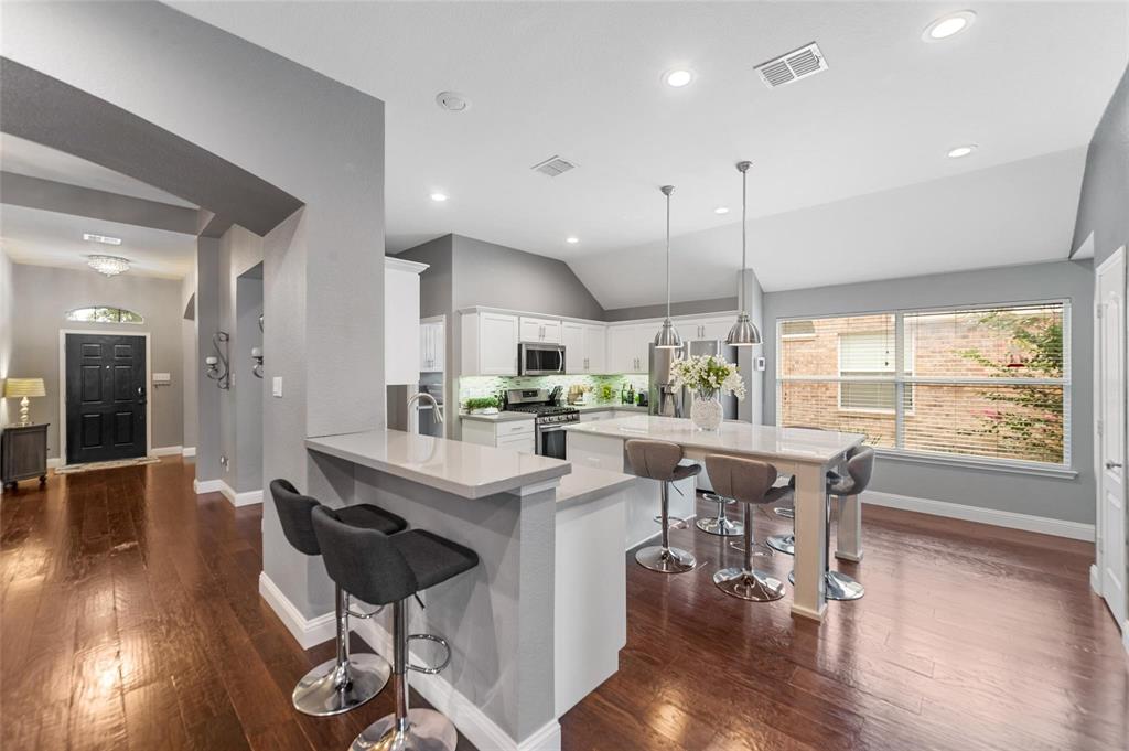1551 Crystal Pass Allen, TX 75002 - Photo 5 of 27 a kitchen with stainless steel appliances granite countertop a stove a refrigerator a kitchen island with chairs and wooden floor