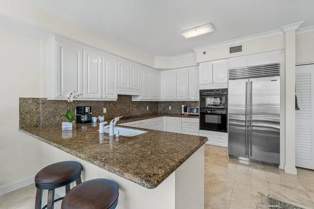 a kitchen with stainless steel appliances granite countertop a sink refrigerator and cabinets