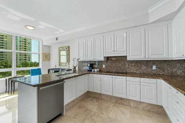 a kitchen with granite countertop a sink and white cabinets