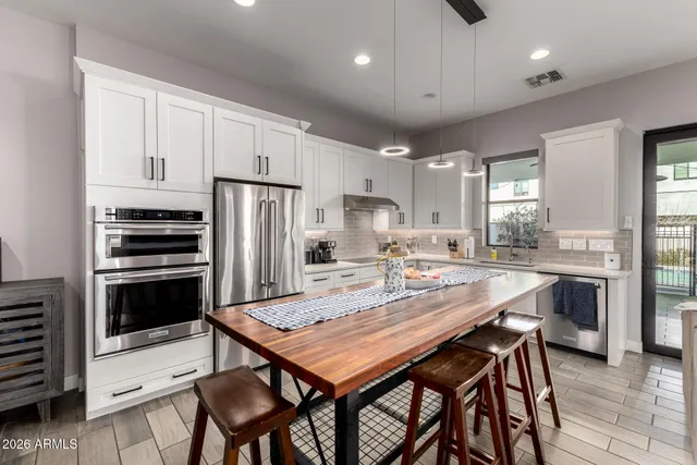 a kitchen with stainless steel appliances kitchen island granite countertop a table chairs sink and cabinets