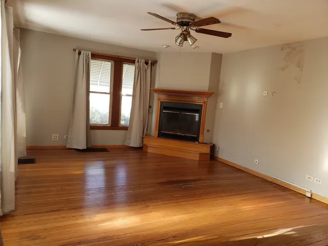 a view of empty room with wooden floor and fireplace