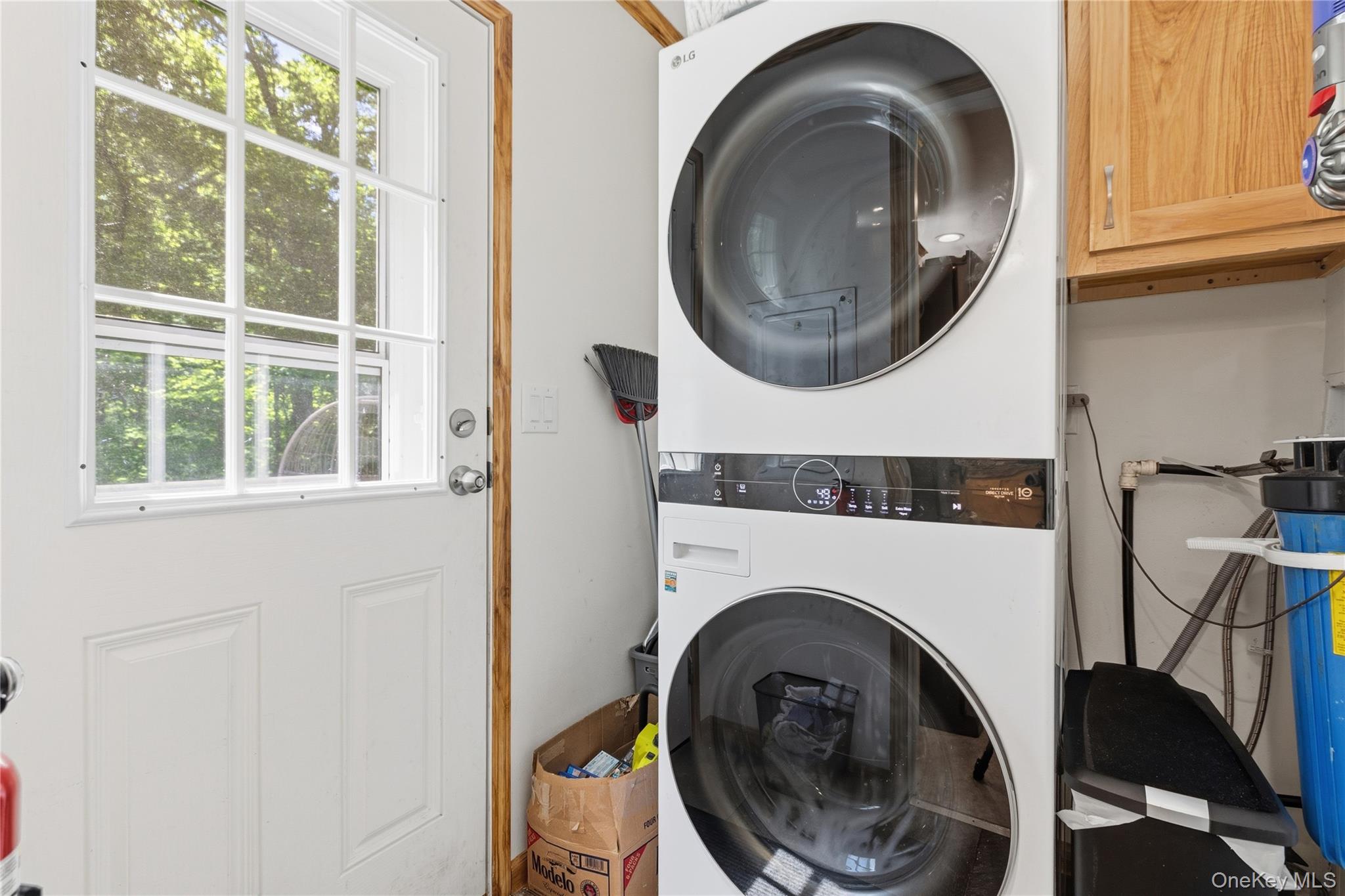 239-241 Fosler Road Highland, NY 12528 - Photo 33 of 42 Dedicated laundry area featuring a stacked washer and dryer unit, wood-finish cabinetry, and a water filtration system