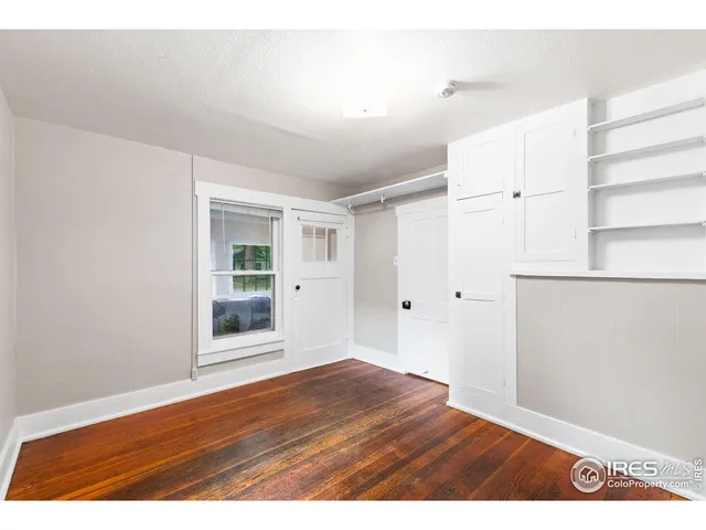 a view of an empty room with wooden floor and windows