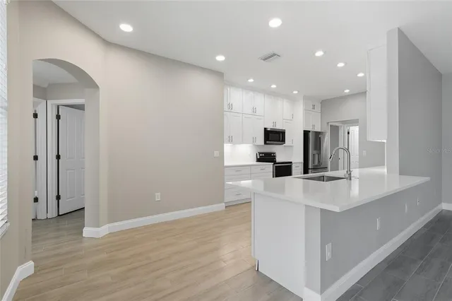 a large kitchen with stainless steel appliances a large counter top and wooden floors