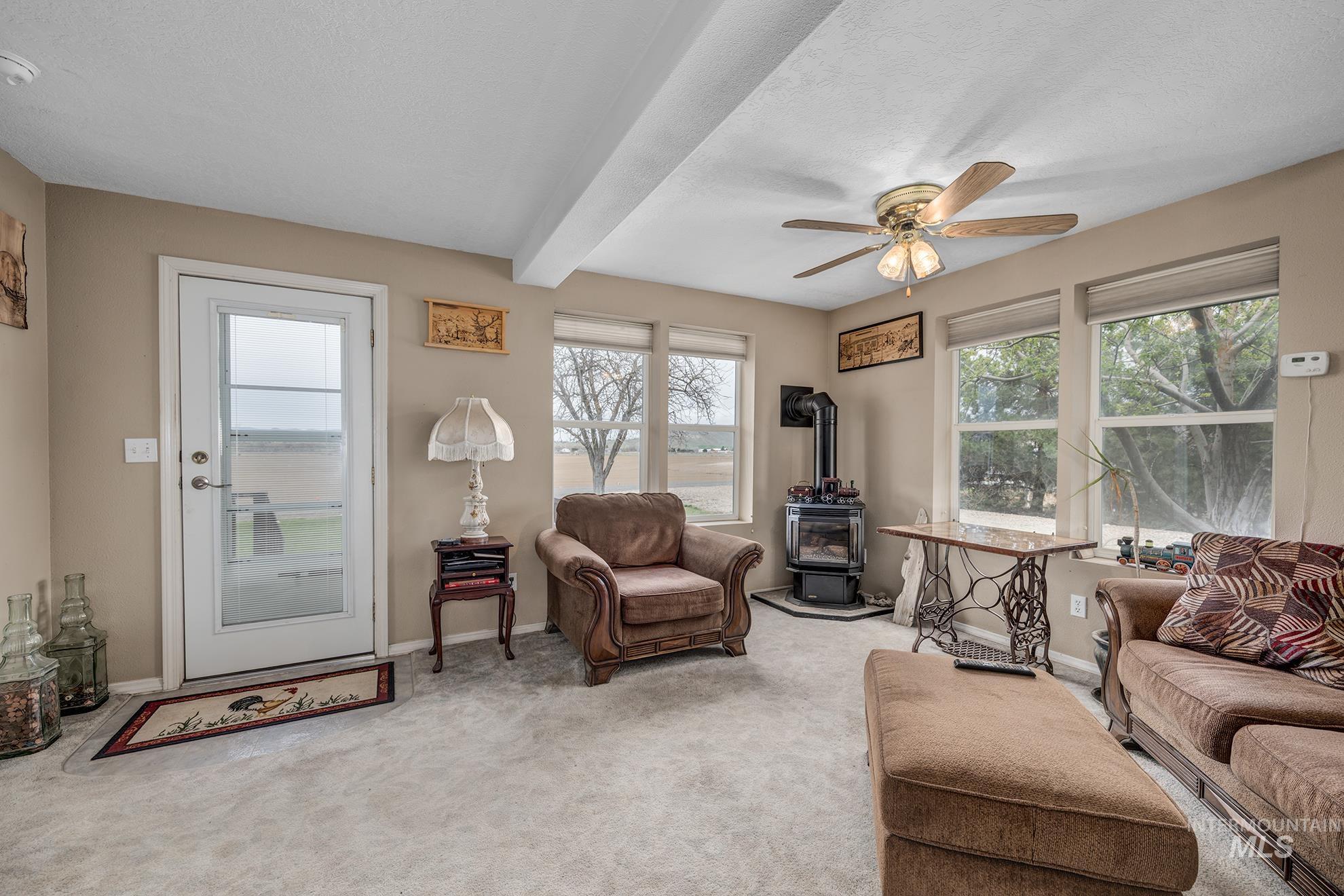 1363 Ross Road Weiser, ID 83672 - Photo 4 of 47 Living room with a wood stove, beamed ceiling, light colored carpet, a ceiling fan, and a textured ceiling