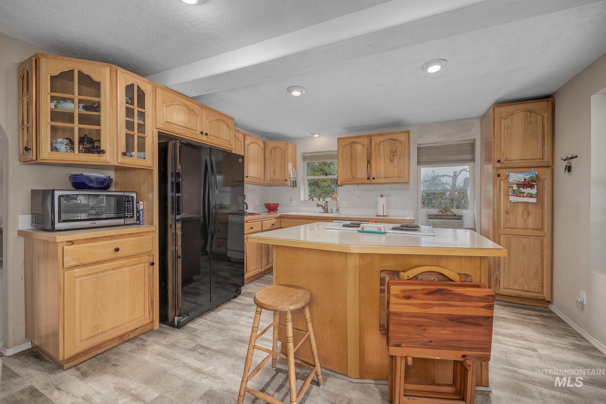 1363 Ross Road Weiser, ID 83672 - Photo 7 of 47 Kitchen featuring glass fronted cabinets, light countertops, freestanding refrigerator, and light wood finished floors