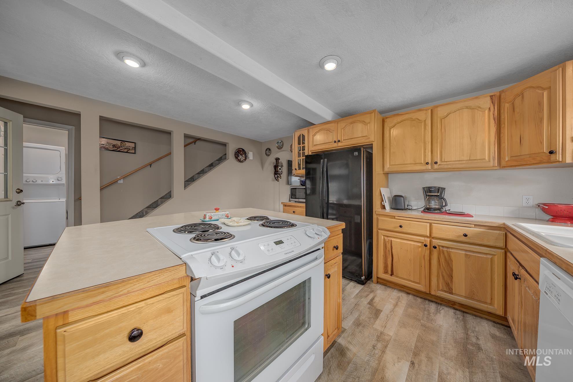 1363 Ross Road Weiser, ID 83672 - Photo 9 of 47 Kitchen featuring white appliances, a center island, light wood-style floors, glass fronted cabinets, and stacked washing machine and dryer