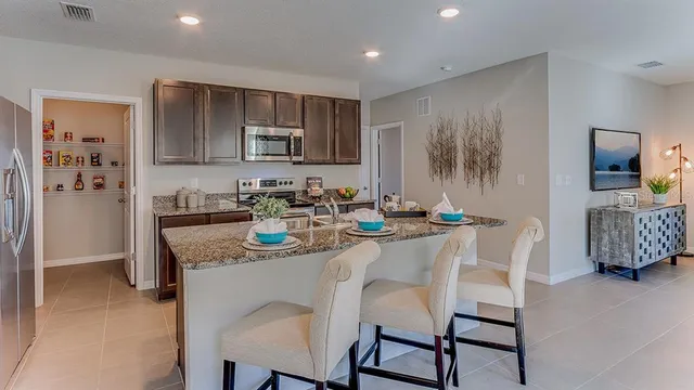 a kitchen with granite countertop a sink and chairs